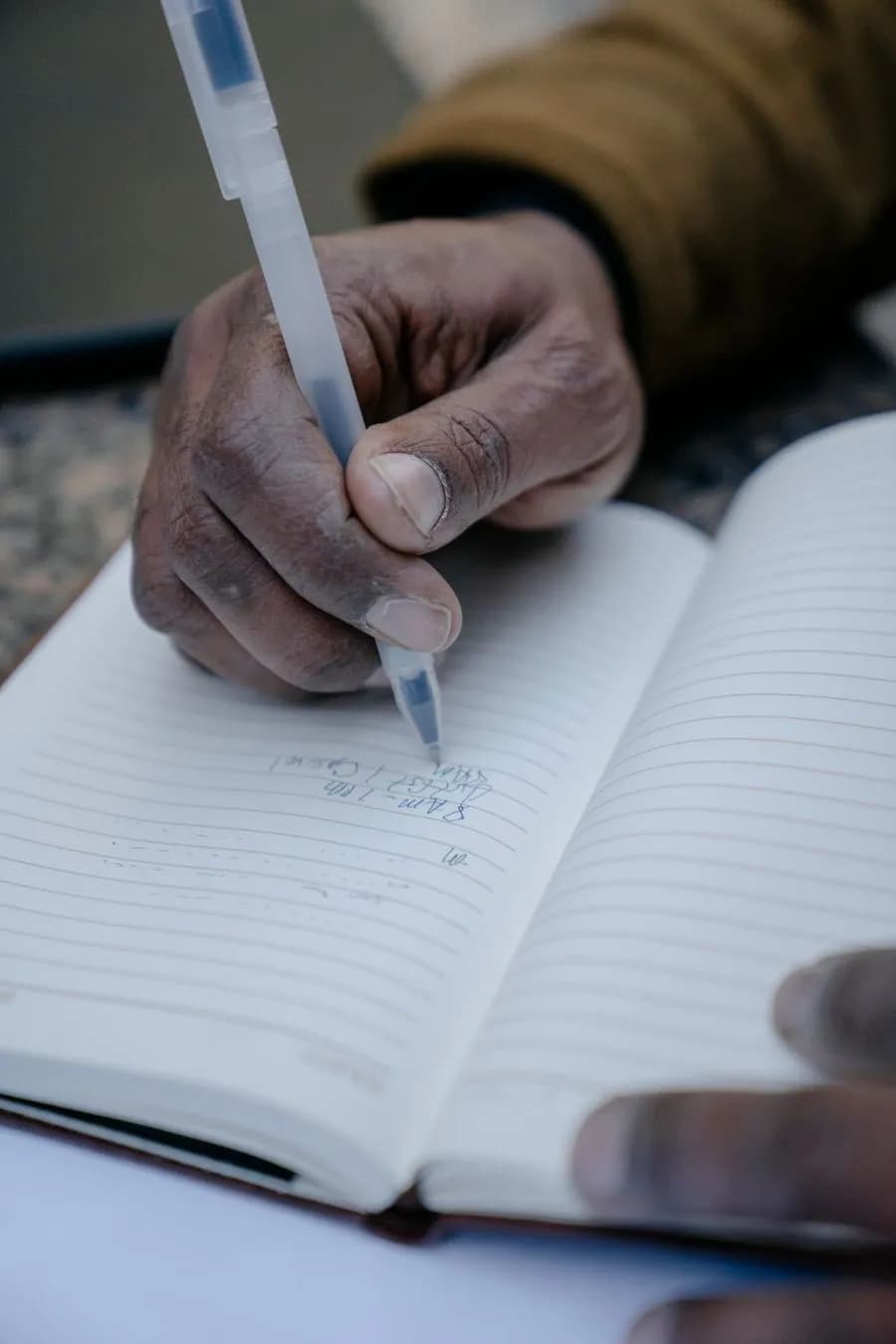 A hand writing with a pen in a notebook